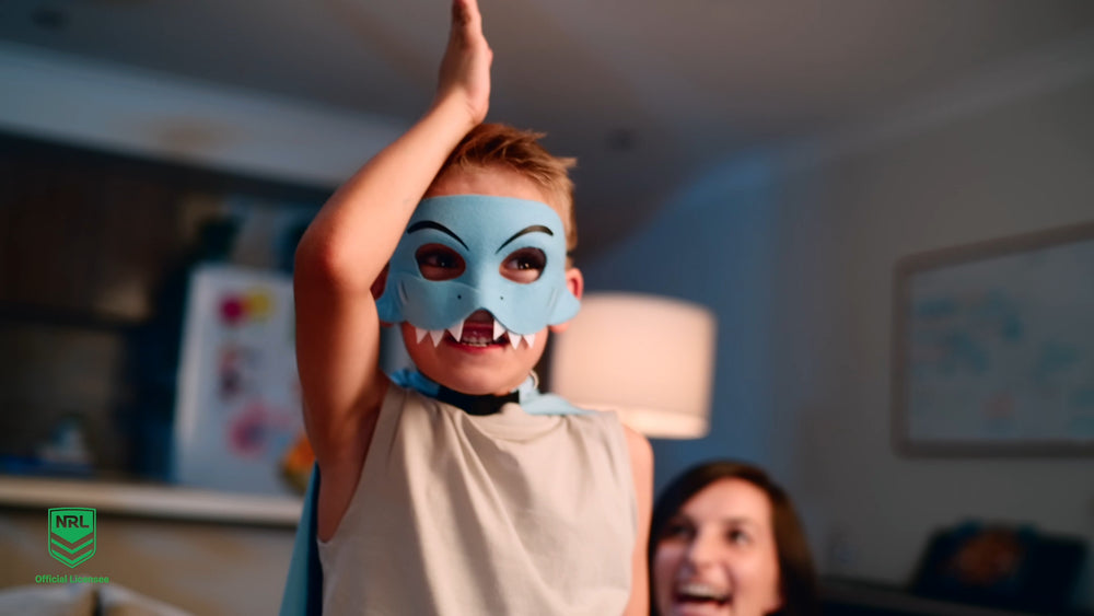 Boy wearing the Cronulla Sharks NRL mask and youth supporter cape