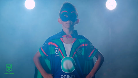 Boy wearing the New Zealand Warriors NRL mask and youth support cape