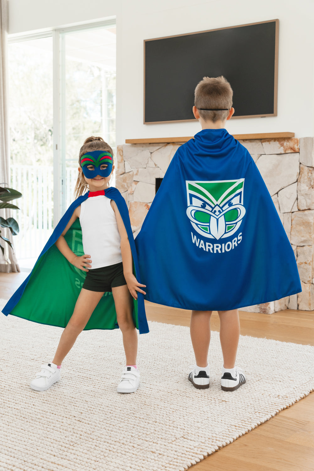 Girl and boy wearing the New Zealand Warriors NRL mask and youth support cape