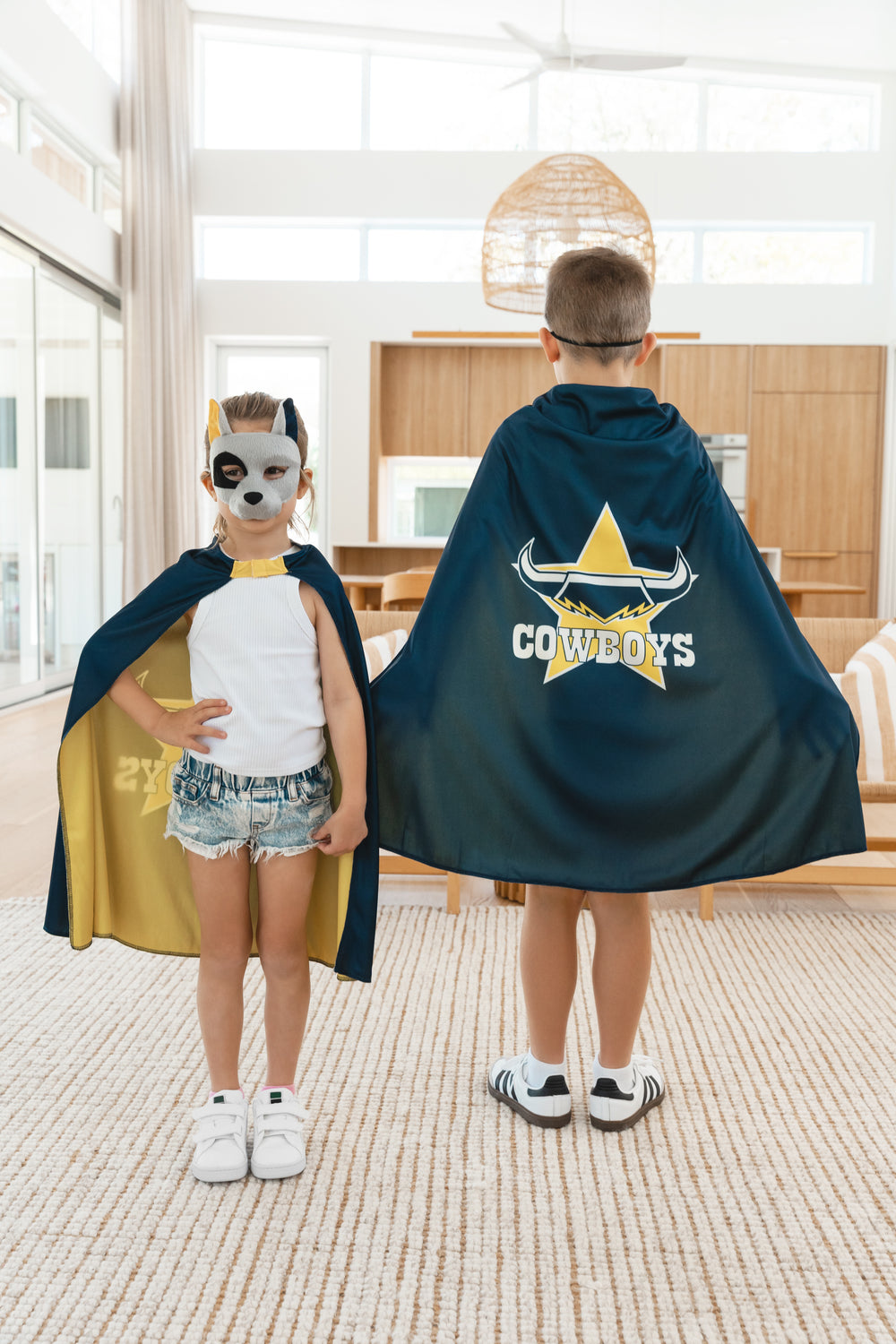 Girl and boy wearing the North Queensland Cowboys NRL mask and youth supporter cape